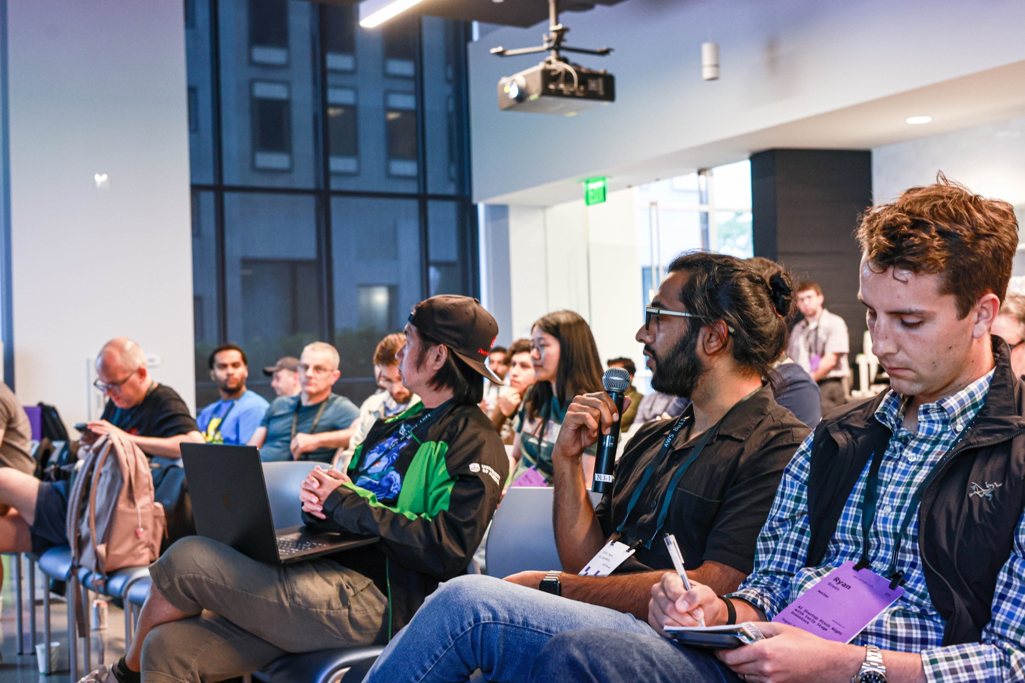 Jas holding a microphone during a discussion with other attendees.